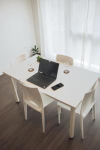 un ordinateur portable assis sur une table blanche avec des chaises dans l'établissement Twenty Business Flats Le Mans Ouest, au Mans