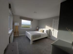 a bedroom with a white bed and a window at Sunny Hill View in Lahinch