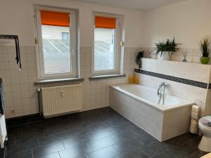 a bathroom with a bath tub and two windows at Pension 71 in Mittelbach