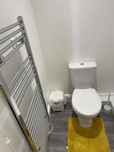a bathroom with a white toilet and a yellow rug at Small room in Horfield 3 in Bristol