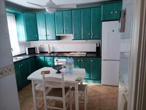 una cocina con armarios verdes y una mesa y sillas blancas. en Gran vivienda unifamiliar céntrica y cercana al mar, en Aguadulce
