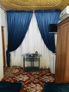 een kamer met een blauw gordijn en een tafel bij Boutique Hotel Parvina in Bukhara