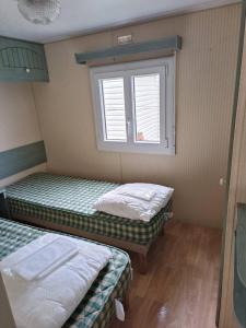 two beds in a room with a window at Mobil-home dans camping calme in Pénestin