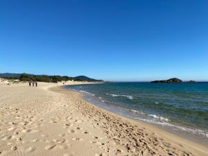 einen Strand mit Fußabdrücken im Sand und im Ozean in der Unterkunft L’Ortensia in Chia