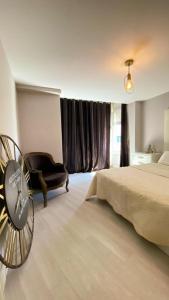 ein Schlafzimmer mit einem Bett, einem Stuhl und einer Uhr in der Unterkunft Penthouse Luxury Granada in Granada