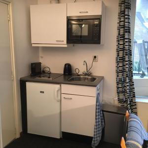 eine kleine Küche mit einer Spüle und einer Mikrowelle in der Unterkunft villa Flore, studio's in Bergen aan Zee