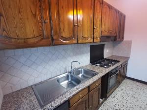 cocina con fregadero, fogones y armarios de madera en La Casa in Collina, en Scansano