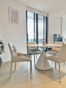 a white living room with a table and chairs at City view designed apartment in Bondi Junction in Sydney