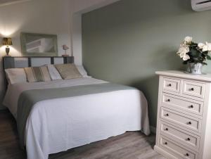 ルーゴにあるB&B La Dolce Rivaのベッドルーム1室(ベッド1台、花の飾られたドレッサー付)