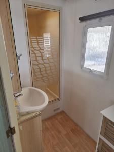 a bathroom with a sink and a glass shower at Mobil-home dans camping calme in Pénestin