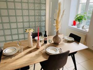 einem Holztisch mit Platten und Vasen darauf in der Unterkunft La roseraie de L arguenon, spacieux appartement centre ville in Jugon Les Lacs