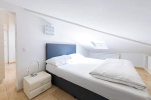 a bedroom with a white bed with a blue headboard at San Carlo Apartments in Lugano