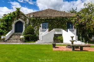 una casa con una valla blanca y un patio verde en Hotel Boutique Casa de Hacienda Su Merced, en Puembo