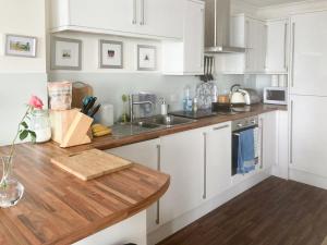 a kitchen with white cabinets and a wooden counter top at Vue De Mer Ella in Shanklin