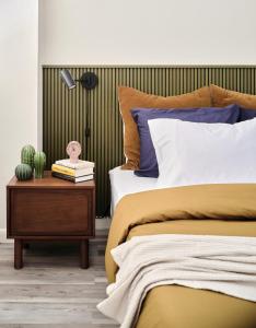 Midcentury Couples Designer Loft - Casa Tuya في أوستن: غرفة نوم بسرير وطاولة جانبية مع صبار