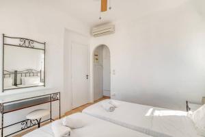 Habitación blanca con 2 camas y espejo. en Thálassa House - Walking distance to Naoussa en Naousa