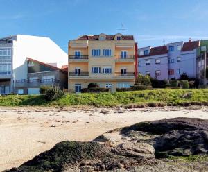 ein Gebäude am Strand mit Gebäuden im Hintergrund in der Unterkunft Apartamento Teresa en Vilanova de Arousa in Pontevedra