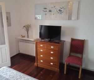 ein Schlafzimmer mit einer Kommode mit einem TV und einem Stuhl in der Unterkunft Apartamento Teresa en Vilanova de Arousa in Pontevedra