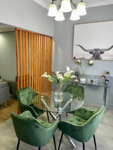 a dining room with a glass table and green chairs at Mdumela Stays 2 Bedroom Modern City Apartment in Pietermaritzburg +23 photos