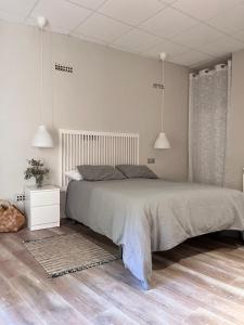 um quarto com uma cama grande e duas luzes pendentes em CASA BASELGA Apartamento em Barbastro