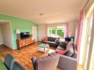 een woonkamer met 2 banken en een televisie bij De Parel van Zeeland met jacuzzi en sauna in Sint Annaland