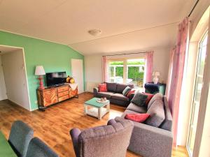 a living room with two couches and a television at De Parel van Zeeland met jacuzzi en sauna in Sint Annaland