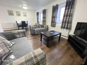 ein Wohnzimmer mit einer Couch, einem Fernseher und einem Tisch in der Unterkunft Howard Farm Holiday Cottages in Bude