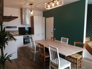 een keuken en eetkamer met een houten tafel en stoelen bij Chez Henri in Les Herbiers