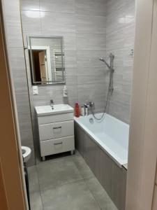 a bathroom with a tub and a sink and a shower at Apartament Garbary 84 in Poznań