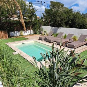a swimming pool in a yard with lounge chairs at Villa Junna in Fréjus