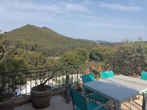 een tafel en stoelen op een balkon met een berg bij LA MADRAGUE- 2P avec piscine privative in Saint-Cyr-sur-Mer