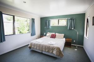 a bedroom with a bed with green walls and windows at Apollo Lodge and Apartment in Wanaka