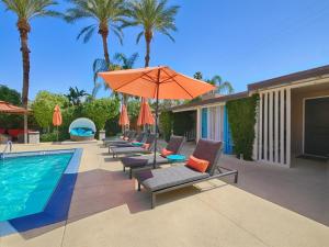 een zwembad met ligstoelen en een oranje parasol bij Little Paradise Hotel in Palm Springs