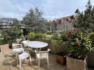 una mesa blanca y sillas en un patio con flores en Côté Jardin - Terrasse, Calme et Cosy en Deauville