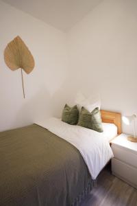 1 dormitorio con 1 cama con sábanas blancas y almohadas verdes en Dein Flughafen Messe Apartment nahe Düsseldorf 2 en Duisburg