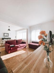 uma sala de estar com um sofá vermelho e um vaso com flores em El Segon Pis em Berga