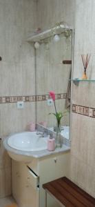 baño con lavabo y jarrón con flor rosa en Bonito bajo cerca del mar, en Benicarló