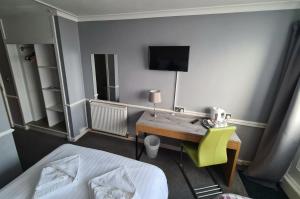 Dormitorio con escritorio, cama y TV en Northumberland Hotel en Edimburgo