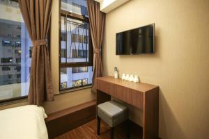 a hotel room with a bed and a television on a wall at Hygge House in Hong Kong