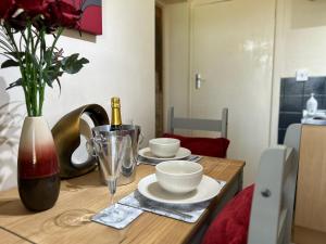 a wooden table with two dishes and a bottle of wine at BOURNECOAST: LOVELY GROUND FLOOR STUDIO APARTMENT, NEAR RIVER & BEACHES - FM3001 in Iford