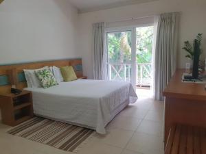 ein Schlafzimmer mit einem Bett und einem großen Fenster in der Unterkunft Ilha Deck Hotel in Ilhabela