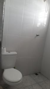 Baño blanco con aseo y pared blanca en Casa das Gaivotas, en Itanhaém