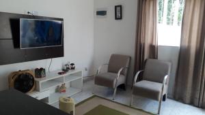 a living room with two chairs and a flat screen tv at Casa das Gaivotas in Itanhaém
