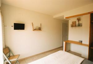 Sant Llorenç de la Muga的住宿－Hostal de l'Aigua，卧室配有一张床,墙上配有电视。