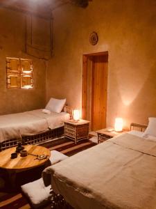 Zimmer mit 2 Betten, einem Tisch und 2 Lampen in der Unterkunft Tanirt ecolodge in Siwa