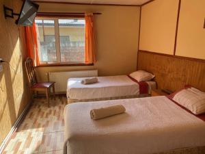 a hotel room with three beds and a window at Nikos II Adventure in Puerto Natales