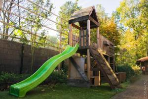 a playground with a green slide in a yard at Le Petit Chalet avec hottub. in Sint-Gillis-Waas