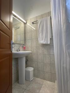La salle de bains est pourvue d'un lavabo, de toilettes et d'un miroir. dans l'établissement Flo's Apartments, à Mesolongion