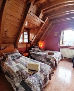 a attic bedroom with three beds in a room at Alojamiento Rural Ostau Era Nheuada in Aubert