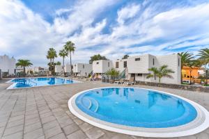 a large swimming pool with palm trees and buildings at Beach Apartment Bungamericas - Sea View Playa de las Americas in Playa de las Americas